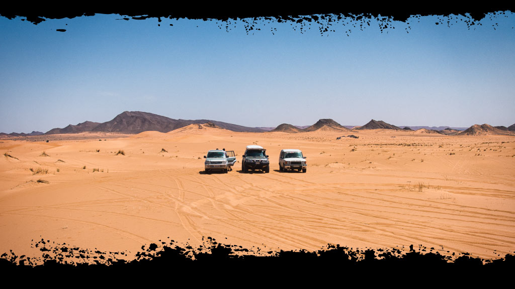 Tres 4x4 en un paisaje desértico de arena durante una ruta 4x4 por Marruecos.