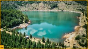 Un 4x4 parado junto a un lago azul de montaña de Albania durante una ruta por los Balcanes.