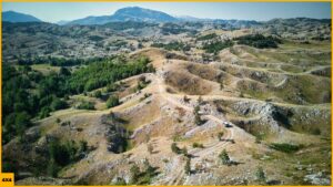 Foto aérea de un 4x4 circulando por pistas de montaña entre prados durante una ruta en 4x4 por Montenegro en los Balcanes